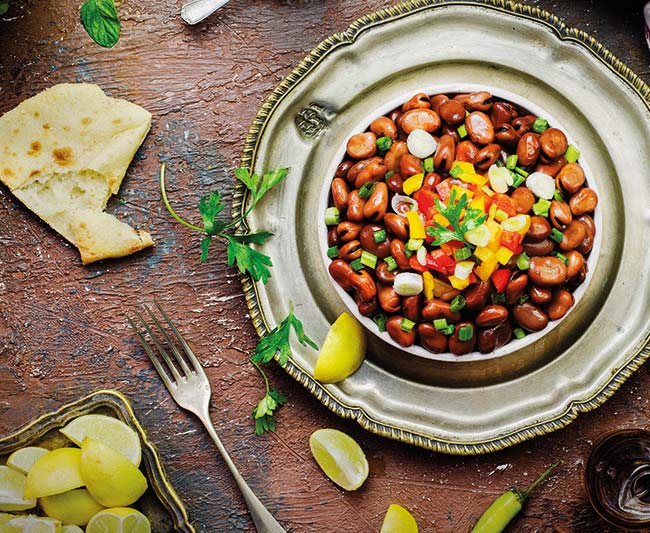 Arabic cuisine; Egyptian traditional dish Ful medames.Middle Eastern delicious breakfast with cooked Fava beans. Served with lemon,cumin,olive oil,salt,pita bread,cup of tea and fresh mint.