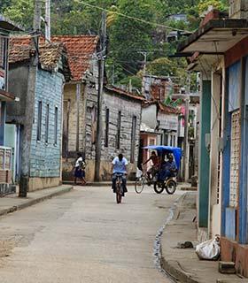 man riding a bike and a rickshaw in the backstreets of havana cuba