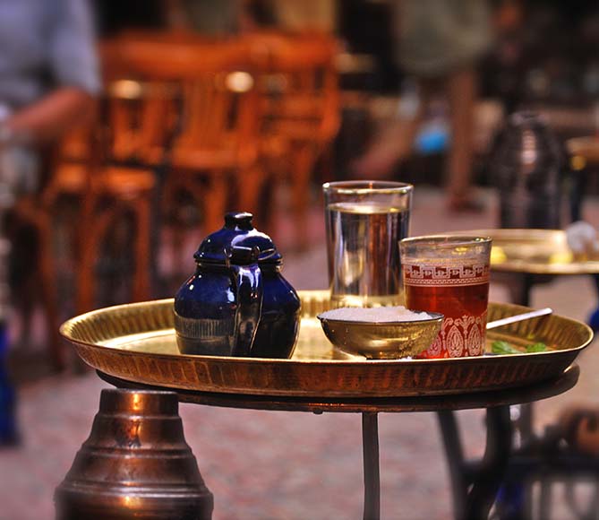 traditional egyptian tea served on a gold tray with a glass of water