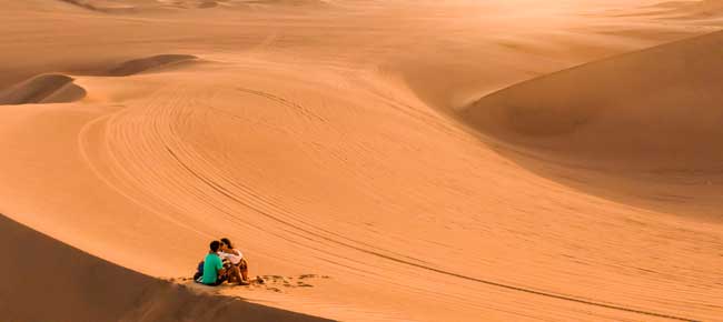 Syoung romantic couple recently married in huacachina in the desert try sand boarding whilst on their honeymoon