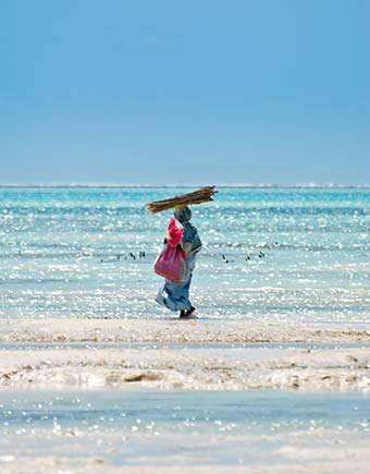 tanzanian woman walking on the beach in zanzibar