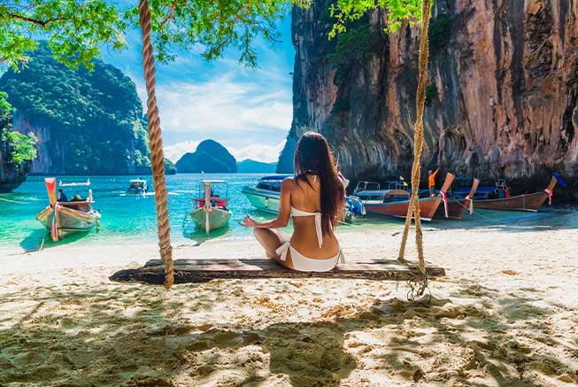 a travelling woman relaxes on the beach in Thailand overlooking the beautiful water