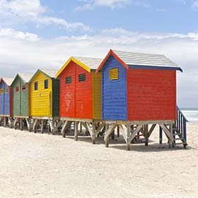 a line of colourful houses on a beach in cape town for summer