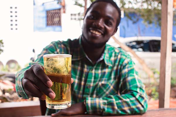 man in zimbabwe holding up a glass of lion larger beer at a beer festival