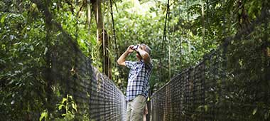 Costa Rica solo travel holiday tourist exploring the sky walks in Monteverde cloud forest spotting wildlife in the tree tops