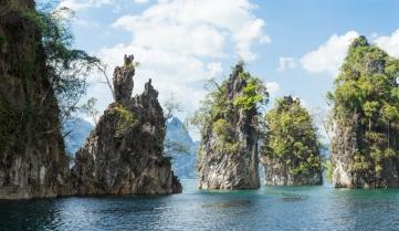 Huge limestone cliffs rising up on a open lake at Khao Sok National Park, Thailand.